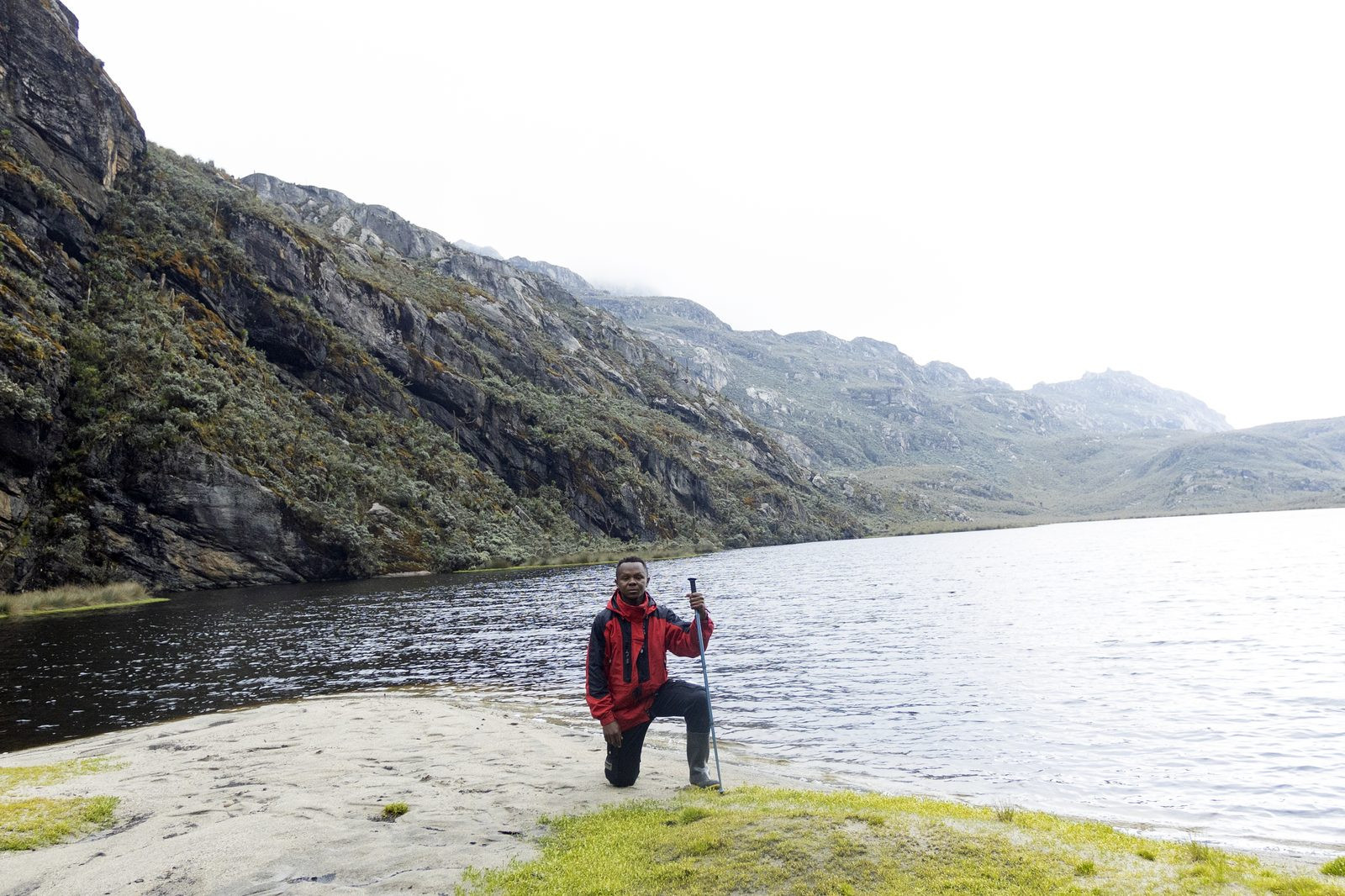 Guide kneeling beside a mountain lake